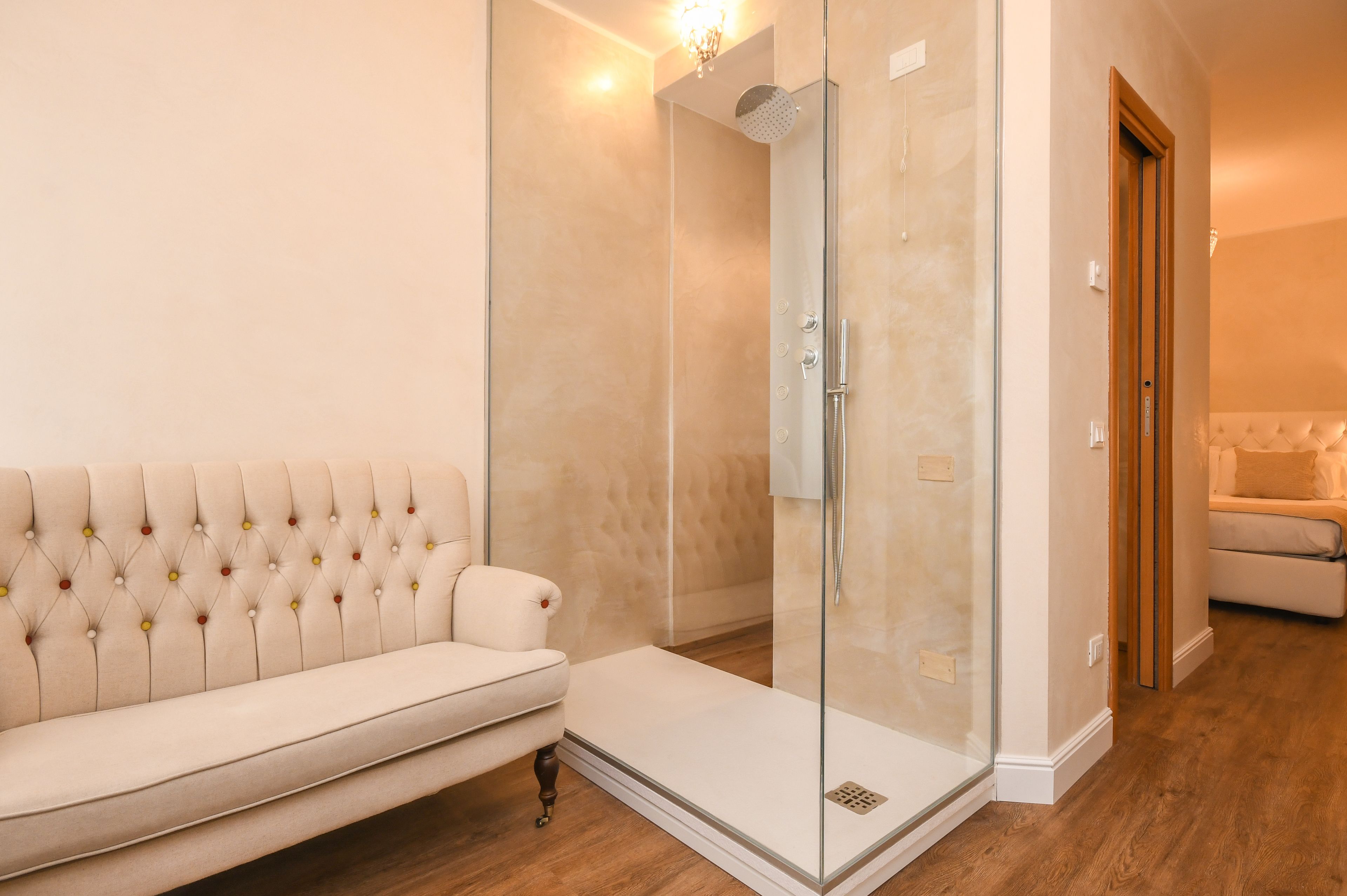 Un bagno moderno con cabina doccia in vetro, una panca imbottita bianca e un pavimento in legno.