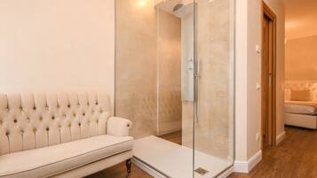 Un bagno moderno con cabina doccia in vetro, una panca imbottita bianca e un pavimento in legno.