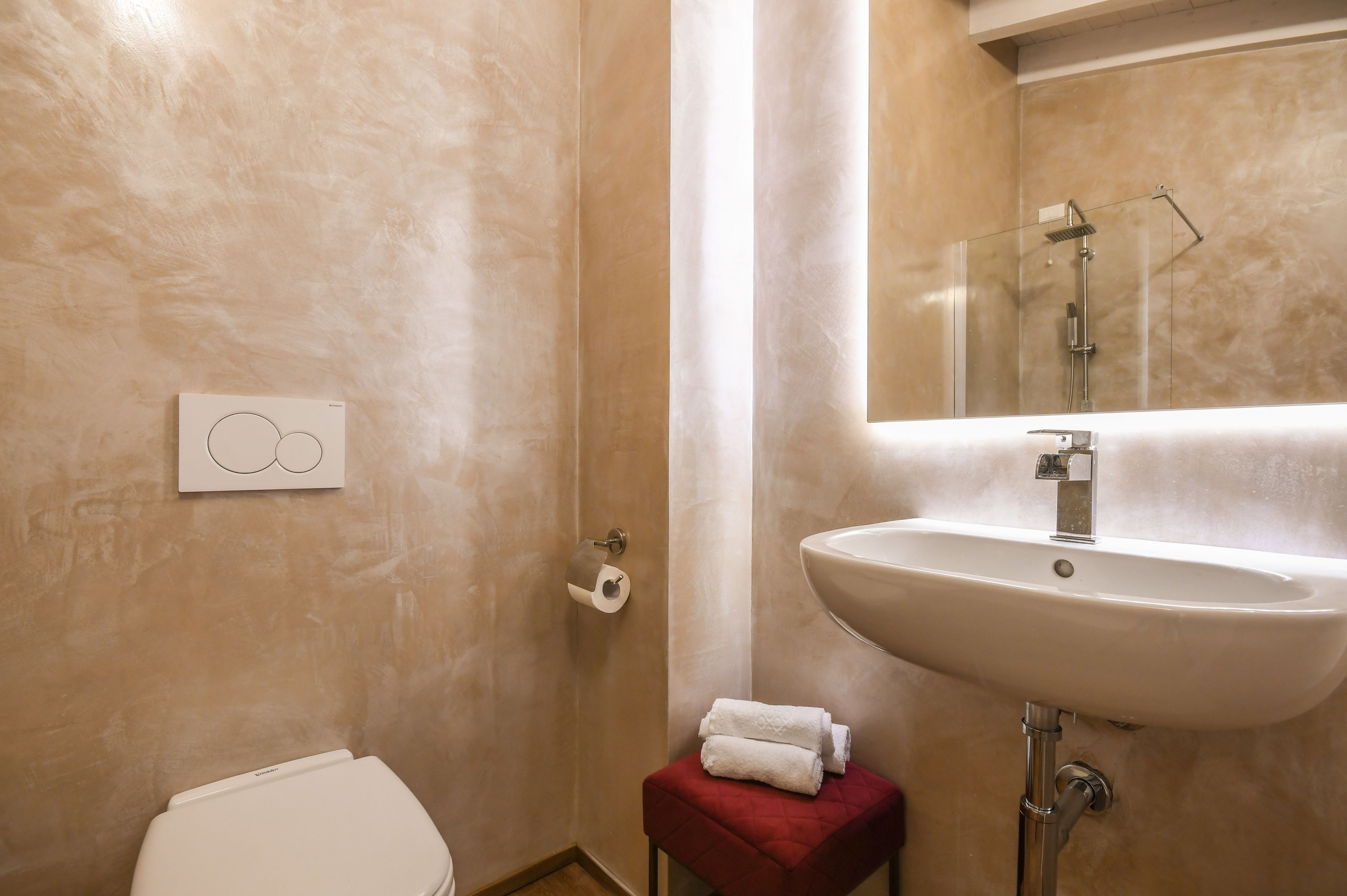 Un baño con inodoro, lavamanos y espejo.