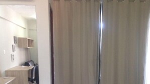 Une chambre d’hôtel avec un lit, un bureau et une chaise. On peut apercevoir la salle de bain à travers une porte.