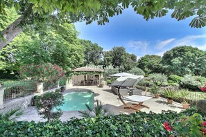 A pool area with a covered seating area, surrounded by lush greenery and a pergola. - Bastide for rent 10 min from Aix-en-Provence amidst vineyards (Aix-en-Provence)