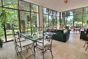 A spacious room with large glass windows, a glass-top dining table, and comfortable seating. - Bastide for rent 10 min from Aix-en-Provence amidst vineyards (Aix-en-Provence)