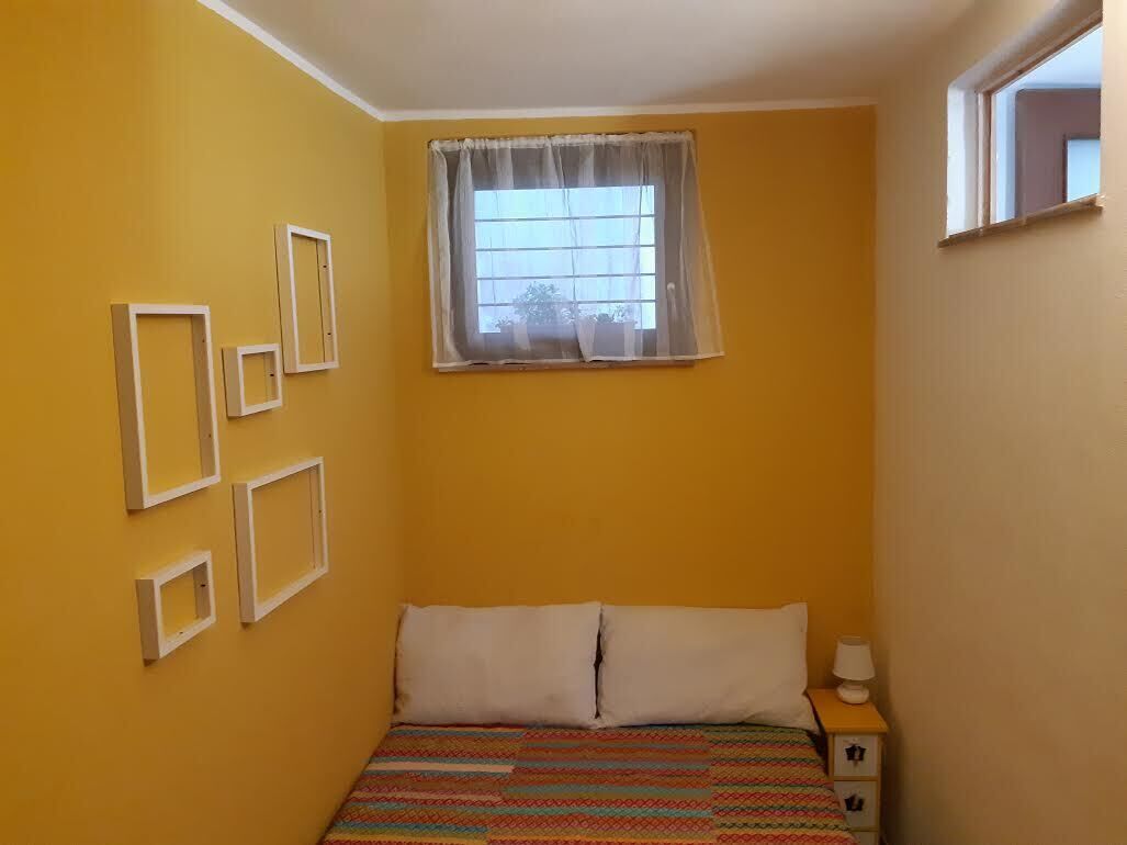 Une chambre à coucher comprenant un lit, une table de chevet, une fenêtre avec des rideaux et des cadres photo accrochés au mur.