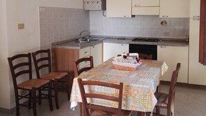 Une cuisine compacte avec un coin repas, comprenant une table avec des chaises, un four encastré et un chauffe-eau.