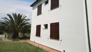 Un bâtiment blanc avec quatre fenêtres et un palmier en arrière-plan.
