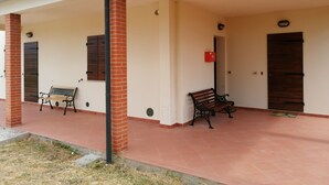 Un espace extérieur abrité comprenant deux bancs, une boîte aux lettres rouge et une porte.