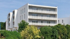 A multi-story residential building with balconies, surrounded by greenery. - Appartement Neuf et équipé, près des Antilles (Jonzac)