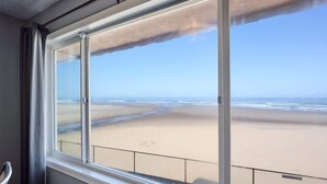 Una habitación con un amplio ventanal con vistas a la playa.