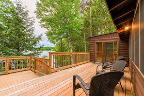 Una terraza de madera con vista a un lago, rodeada de árboles.
