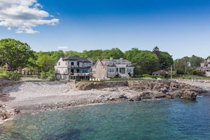 Situated on a rocky shoreline, this property offers stunning views of the surrounding greenery and clear blue water.