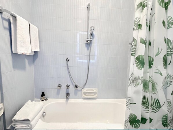 Une salle de bain avec une baignoire, une douche et un rideau de douche orné d’un motif de feuilles.