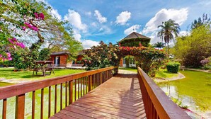 A wooden bridge leading to a gazebo surrounded by lush greenery and a pond. - Casa Tranquila Miami, A Luxury Ranch-Style Retreat (Miami)