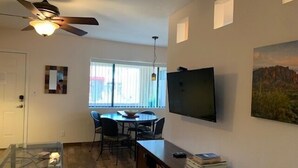Un espacio habitable compacto con comedor, televisor montado en la pared y ventilador de techo.