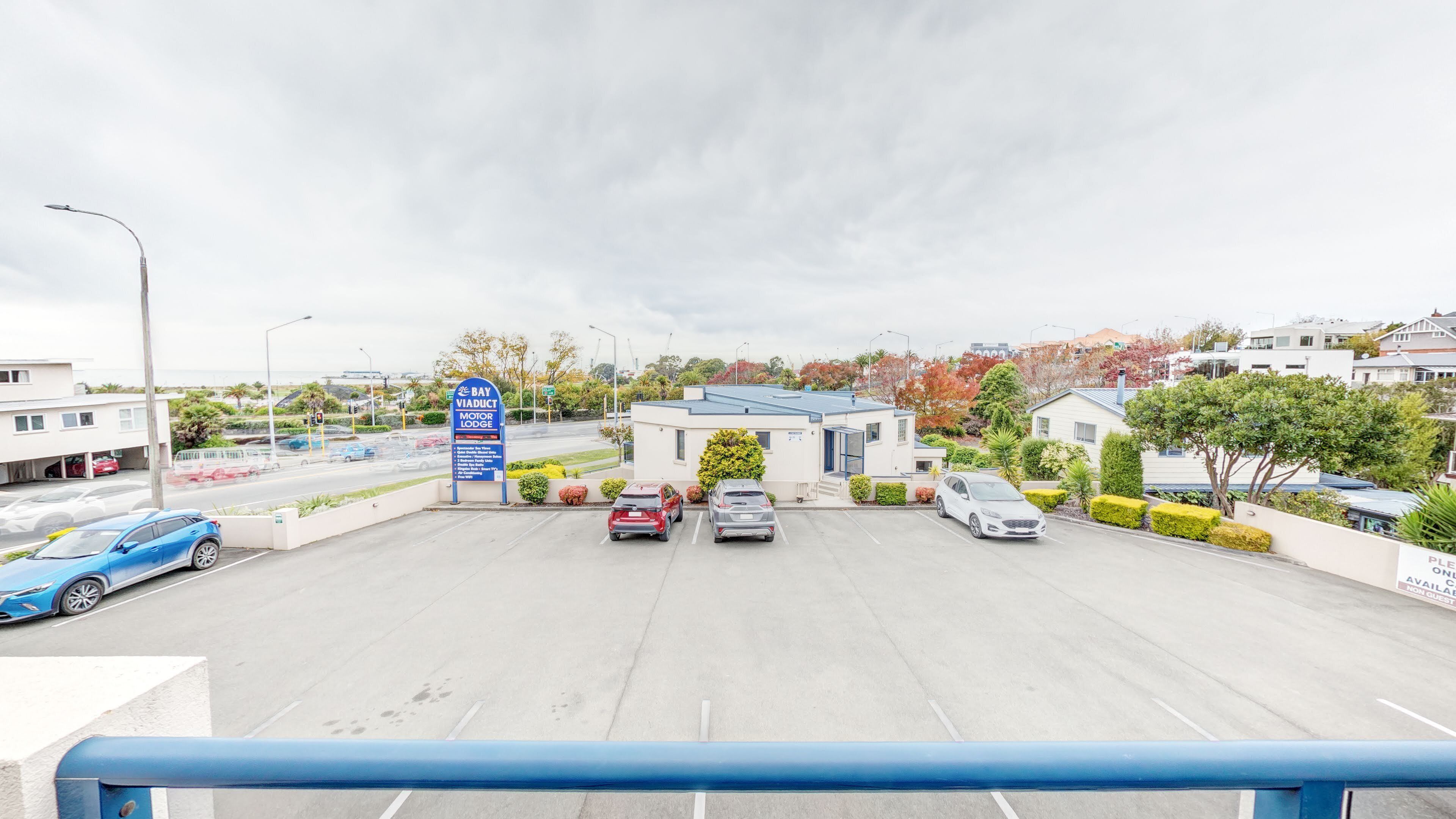 A parking lot with several cars, a motor lodge sign, and a building with a blue roof.