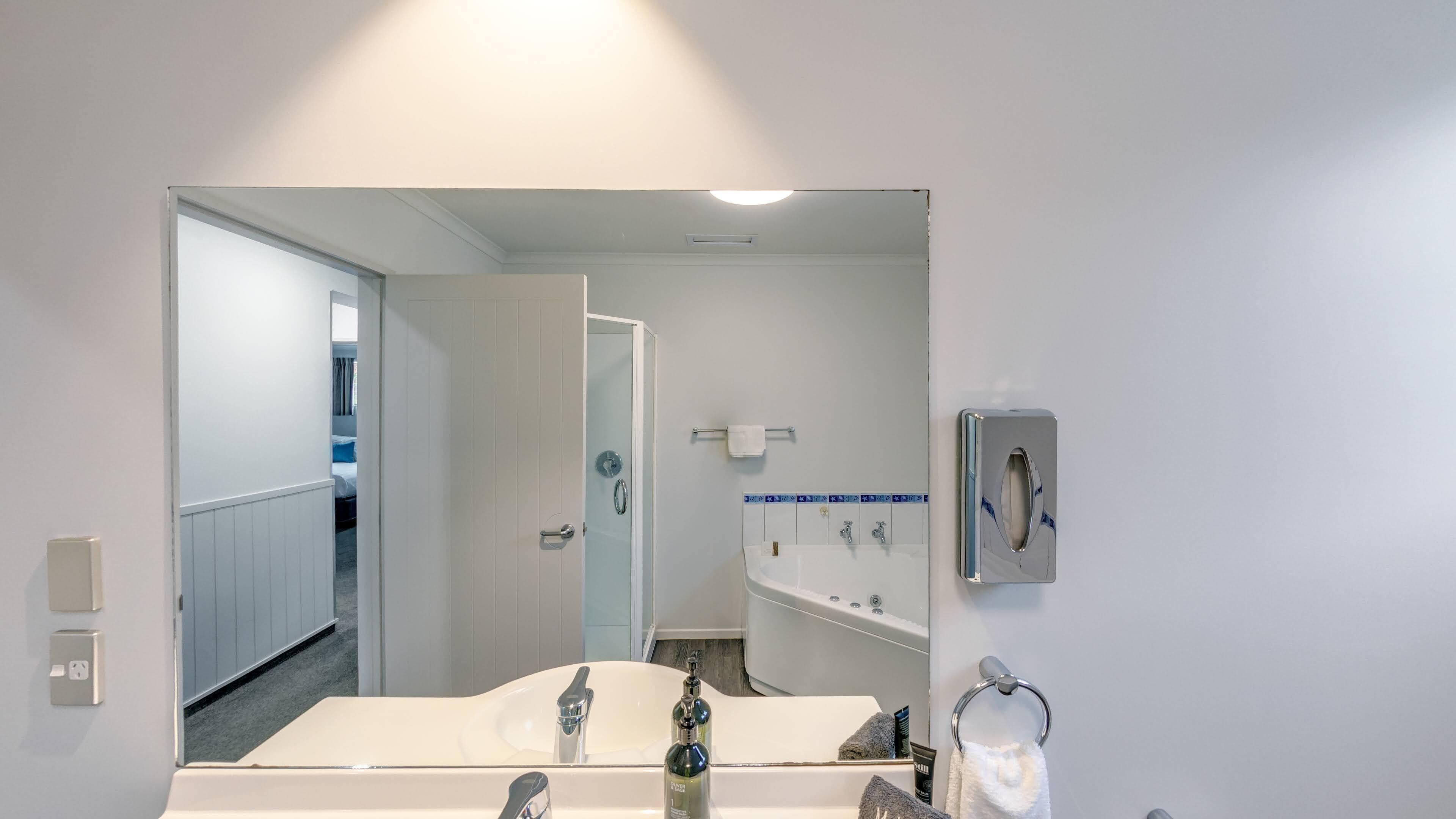 Ein modernes Badezimmer mit einem Waschbecken, einem Spiegel und einem Handtuchhalter.