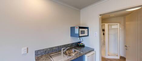 A compact kitchen with a built-in microwave, a stainless steel sink, and a small countertop.