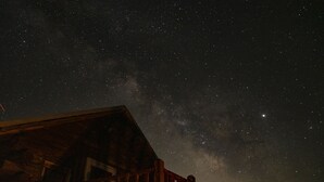 A wooden cabin with a wooden deck under a starry night sky. - Colorado Cabin with Hot tub, sauna, cold plunge! (Colorado)