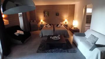 Een moderne slaapkamer met een bed, twee nachtkastjes, een bank, een salontafel en een grote lamp.