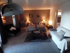 Une chambre moderne avec un lit, deux tables de chevet, un canapé, une table basse et une grande lampe.