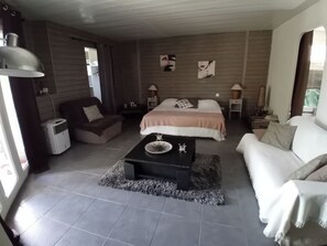 A modern bedroom with a large bed, a sofa, a coffee table, and a desk.