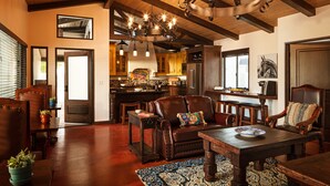 A spacious living room with a fireplace, leather sofas, wooden dining table, and a chandelier. - La Lomita Ranch (San Luis Obispo)