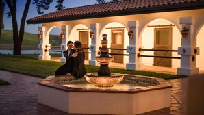 A courtyard with a fountain, a pool, and a building with arched windows and a tiled roof. - La Lomita Ranch (San Luis Obispo)