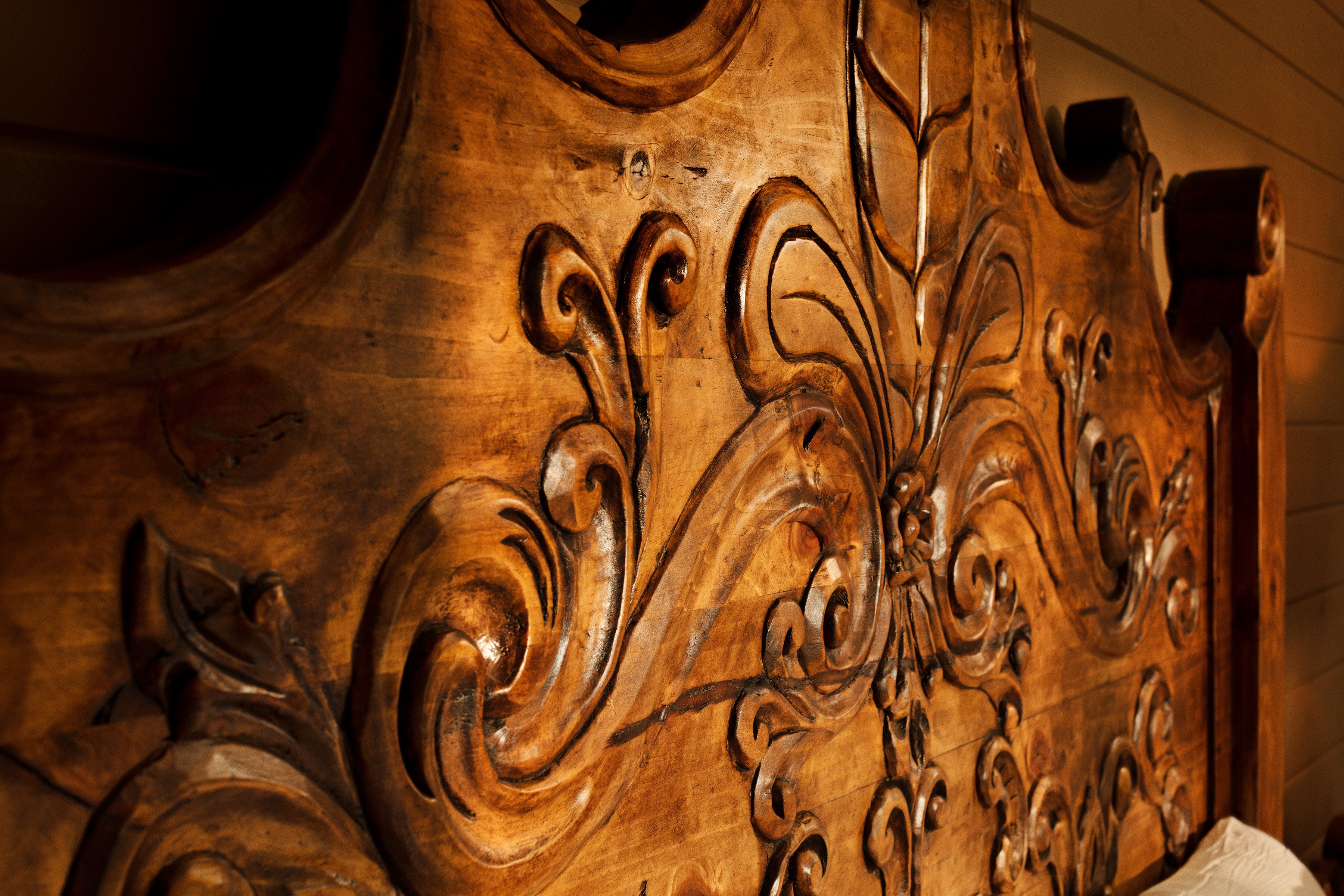 A close-up of a wooden headboard with intricate carvings.