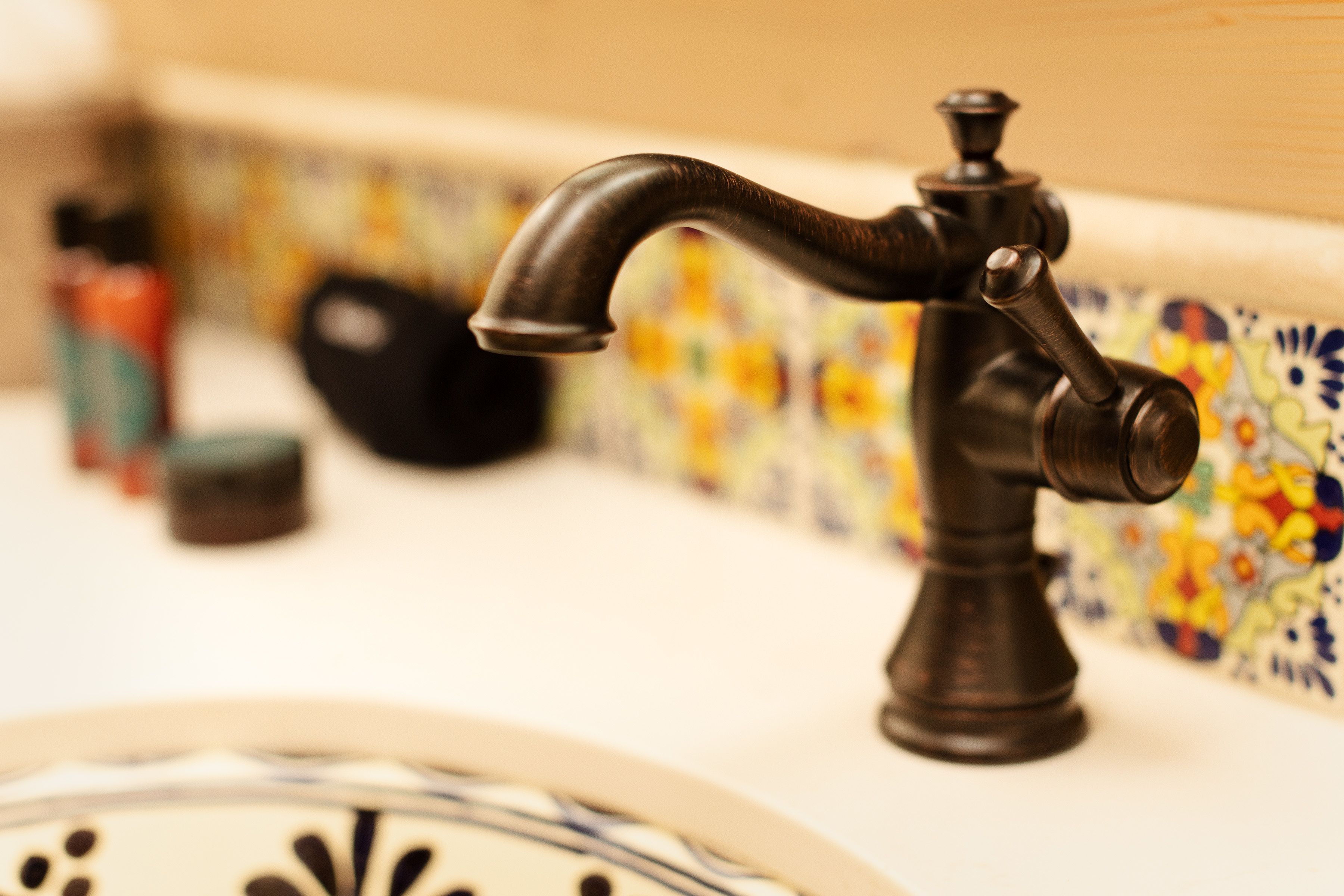 Un baño con un grifo decorativo, un salpicadero de azulejos y un lavabo blanco.