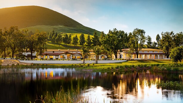 A large, multi-story building with a courtyard and a lake in front. - La Lomita Ranch (San Luis Obispo)