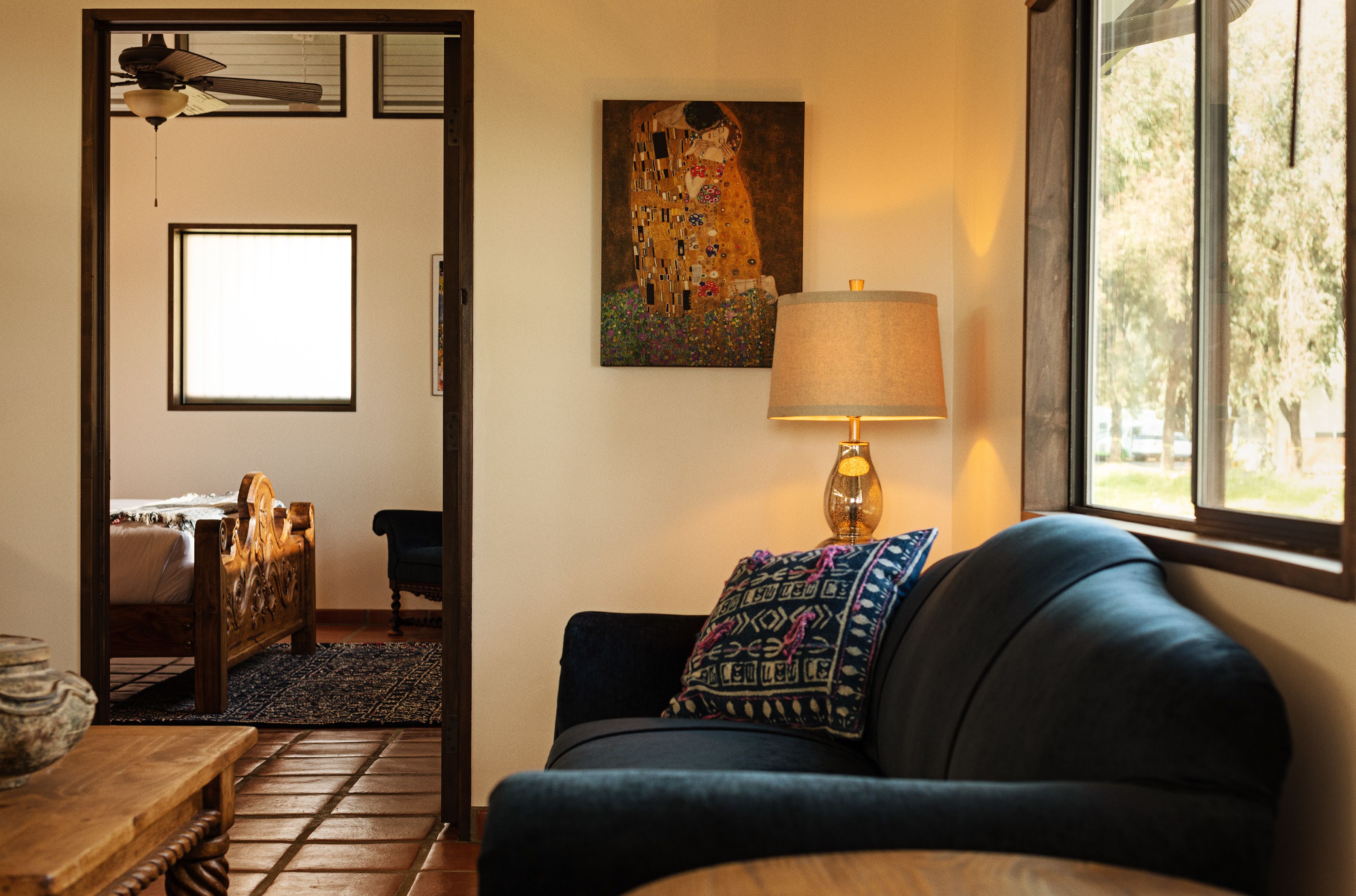 A room with a bed, a blue sofa, a lamp, and a painting on the wall.