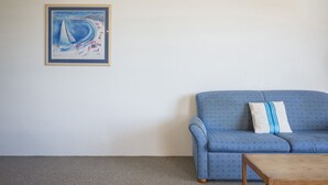 A living room with a blue sofa, a wooden coffee table, and a framed painting on the wall. - San Clemente No. 2. 24 Orvieto Terrace (Kings Beach)