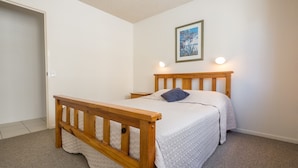 A single bed with a wooden frame and headboard, a bedside table, a nightstand, a wall-mounted light, and a framed picture on the wall. - San Clemente No. 2. 24 Orvieto Terrace (Kings Beach)