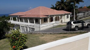 A two-story house with a red roof, white columns, and a balcony. - Rose View Apartment Montego Bay (Montego Bay)