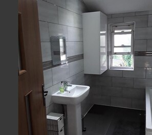 A bathroom with a white sink, a mirror, and a window. - Traithouse (Liverpool)