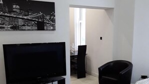 Una sala de estar moderna con un televisor de pantalla plana, un sillón negro y una cama.