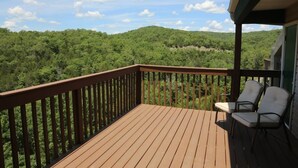 A wooden deck with a railing, two chairs, and a view of a forested hillside. - Top Floor Eagles Nest Condo with Pool and Hot Tub and Lake Views close to Silver (Branson)
