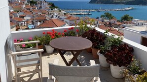 A balcony with a table and chairs overlooking a coastal town with terracotta-roofed buildings and a marina. - Daskios House , Skopelos Chora, a fully equipped house ideal for 2-3 guests (Skopelos)