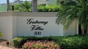 Une enseigne indiquant « Gateway Villas, numéro 500 », avec une allée pavée et un parterre de fleurs.