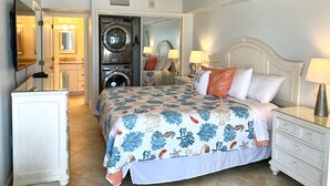 Une chambre d’hôtel équipée d’un lit, d’une table de chevet, d’une commode, d’un ventilateur de plafond et d’une machine à laver.