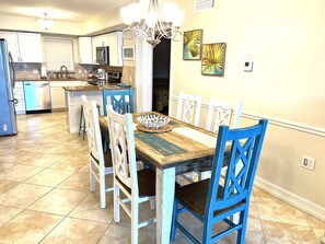 A kitchen with a dining area, featuring a wooden table, blue chairs, and a chandelier.