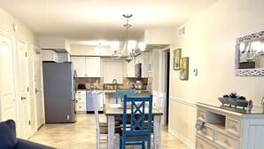 Une cuisine spacieuse avec un coin repas, une chaise bleue et un meuble blanc.