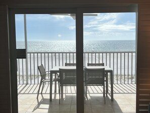 Ein Balkon mit Tisch und Stühlen mit Blick auf einen Strand und den Ozean.