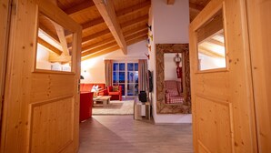 A wooden interior with a high ceiling and a cozy living area featuring a red sofa and a checkered chair. - Finest Penthouse All Seasons Lodge Kaprun (Kaprun)