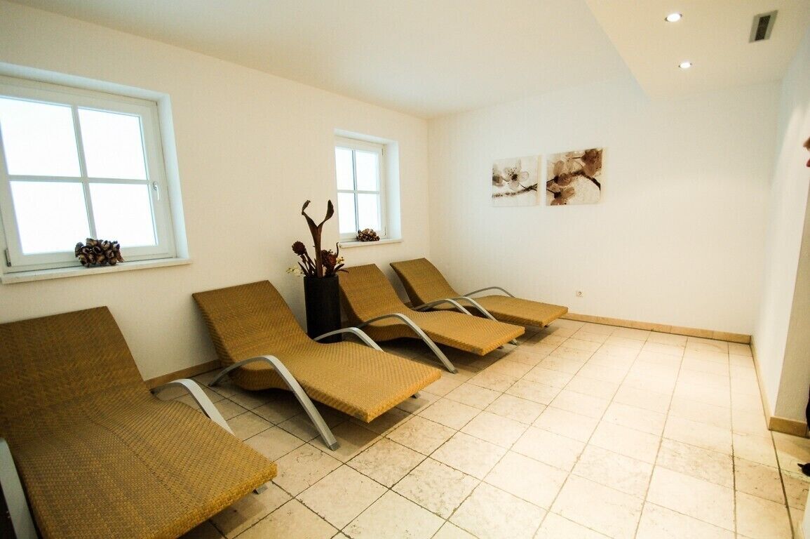 A waiting area with four brown lounge chairs, two windows, and a tiled floor.