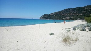 A beach with white sand, clear blue water, and a hilly backdrop. - villa leopoldo, a few minutes away from the most popular beaches (castiadas)
