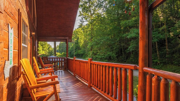 A wooden deck with rocking chairs and a railing overlooking a forested area. - 🐾A Mountain Heart Song🔥Pet-Friendly, Fire Pit, Hot Tub & Gazebo (Sevierville)