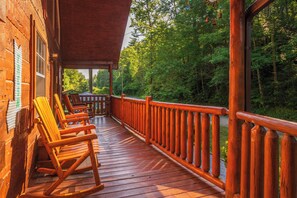 A wooden deck with rocking chairs and a railing overlooking a forested area. - 🐾A Mountain Heart Song🔥Pet-Friendly, Fire Pit, Hot Tub & Gazebo (Sevierville)