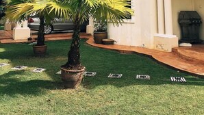 A building with a curved facade, large windows, and a well-maintained lawn with palm trees. - Villa Shamir near KLIA (Sepang)