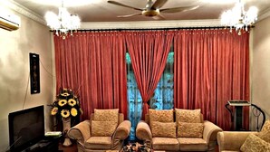 A living room with a sofa set, a coffee table with flowers, a TV, and a red curtain backdrop. - Villa Shamir near KLIA (Sepang)
