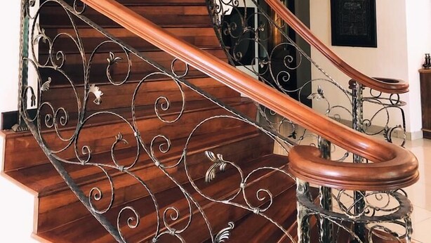 A wooden staircase with ornate metal railings and a chandelier. - Villa Shamir near KLIA (Sepang)